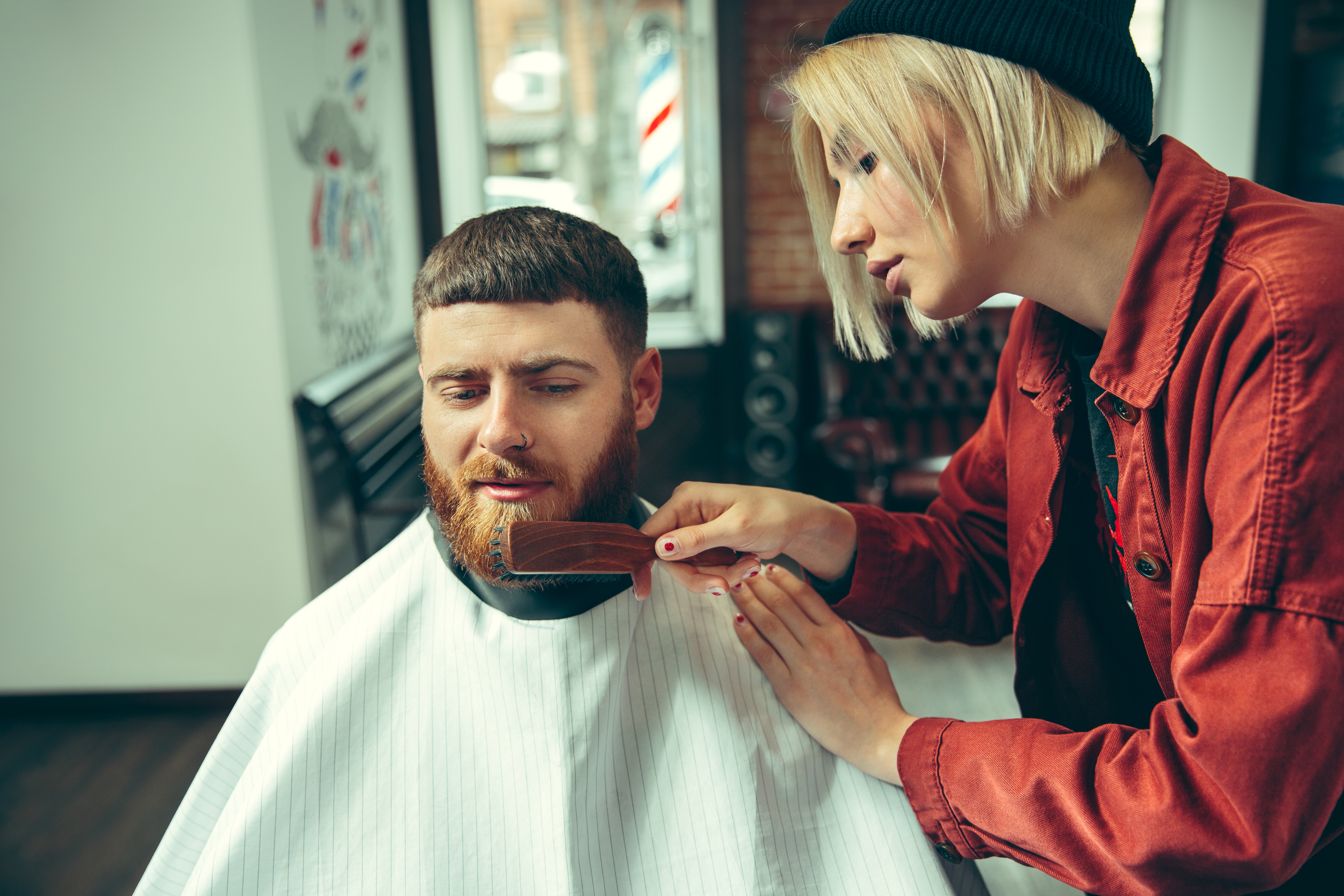 Защо и как да използваме четката за брада? 2 client during beard shaving in barbershop female barber at salon gender equality woman in the male profession